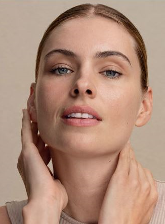 Woman touching her face and neck against a beige background